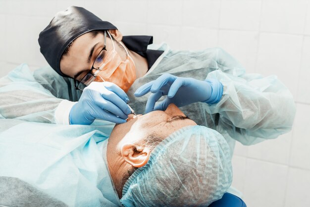 Un joven médico dentista trata a un paciente. Manipulaciones médicas en odontología, cirugía.