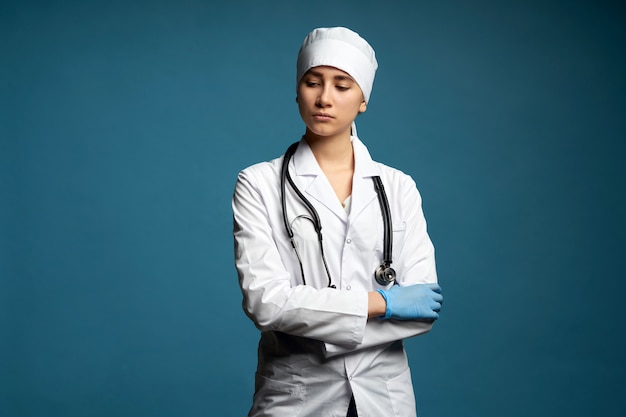 Joven médico con estetoscopio contra la pared azul oscuro, foto de estudio con espacio de copia