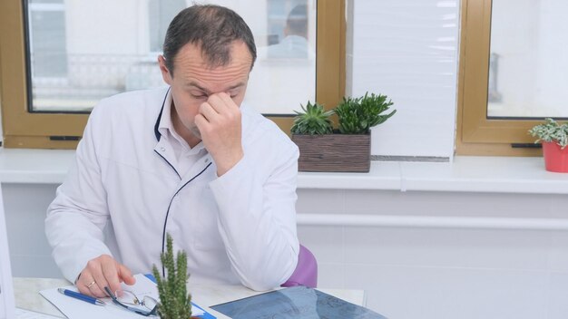 Foto el joven médico se frota los ojos sintiéndose cansado e infeliz.