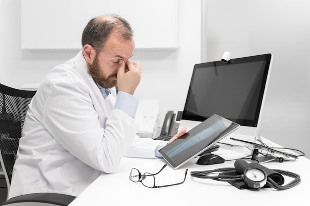 Joven médico frotándose los ojos sintiéndose cansado e infeliz trabajador de la salud estrés y frustración co