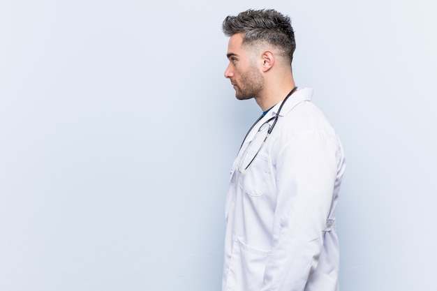 Foto joven médico guapo hombre mirando a la izquierda, de lado plantean.