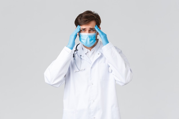 Joven médico guapo en un uniforme blanco con una mascarilla