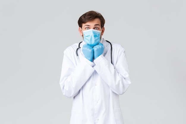 Joven médico guapo en un uniforme blanco con una mascarilla