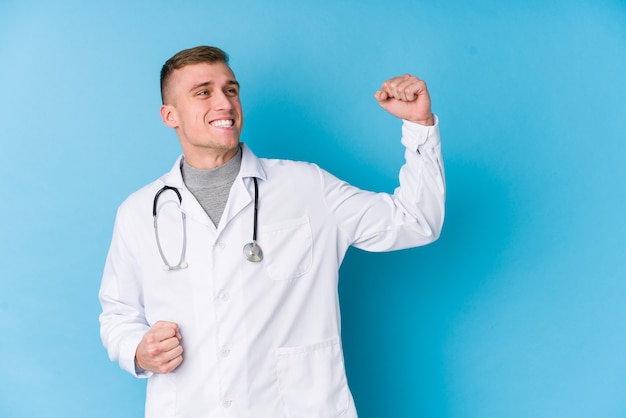 Joven médico hombre levantando el puño después de una victoria