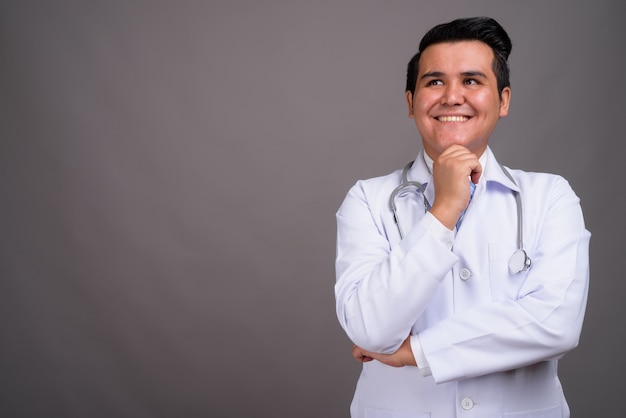 Joven médico hombre multiétnico contra la pared gris