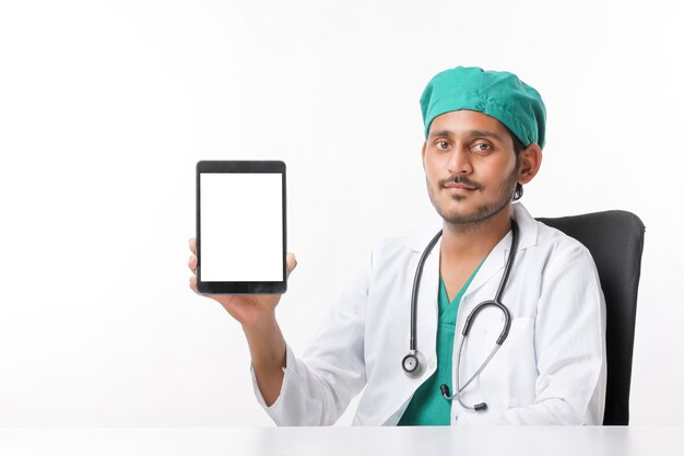 Joven médico indio que muestra la pantalla de la tableta en la clínica.