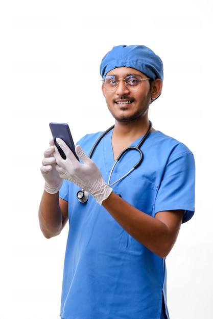 Joven médico indio con smartphone sobre fondo blanco.