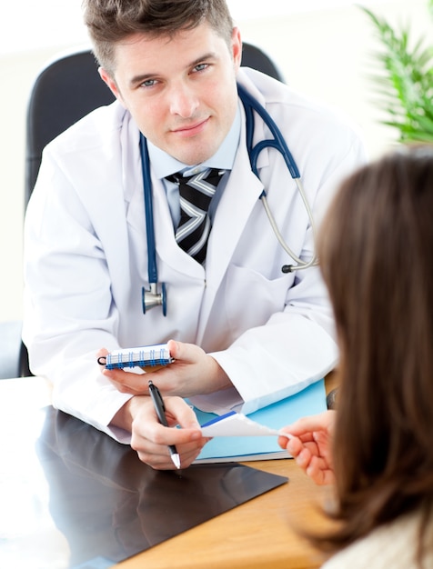 Joven médico masculino dando prescripción a un paciente