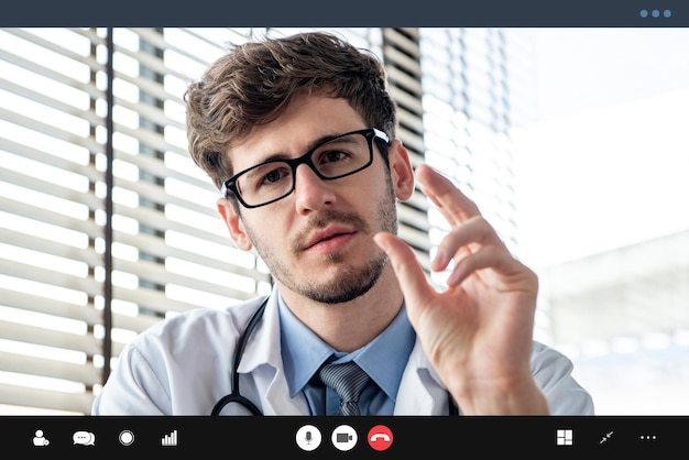 Foto joven médico masculino explicando seriamente algo al paciente a través de una aplicación de videollamadas en línea, conceptos de telesalud