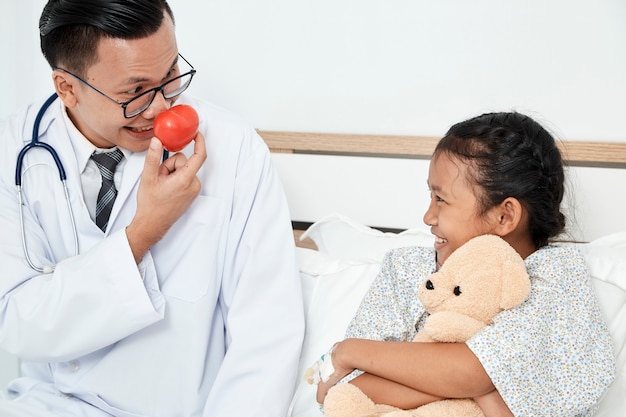 Joven médico masculino pediatra comprobación de niña