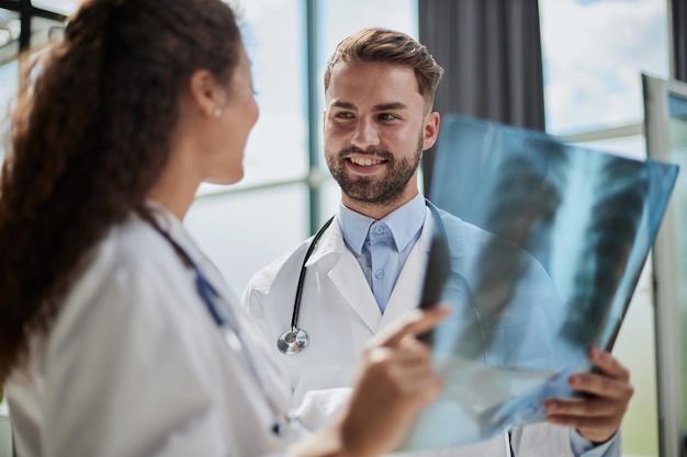 Joven médico masculino serio y competente mirando radiografías en el consultorio médico