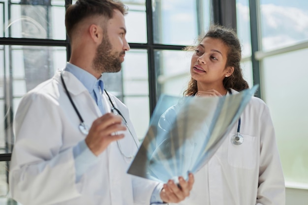 Joven médico masculino serio y competente mirando radiografías en el consultorio médico