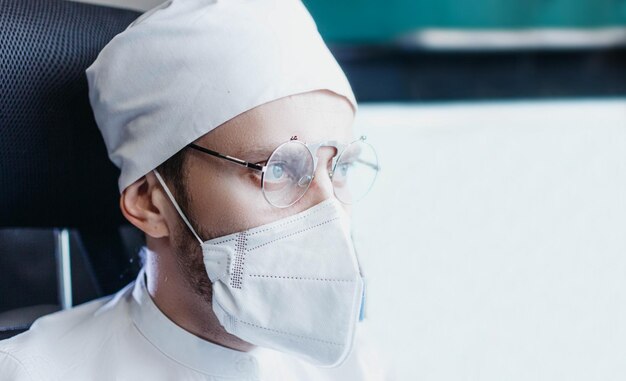 joven médico masculino con uniforme blanco y anteojos en la oficina trabaja