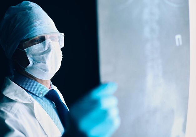 Joven médico mirando la imagen de rayos X sobre fondo blanco aislado