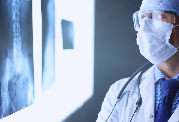 Joven médico mirando la imagen de rayos X sobre fondo blanco aislado