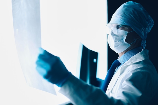 Joven médico mirando la imagen de rayos X sobre fondo blanco aislado