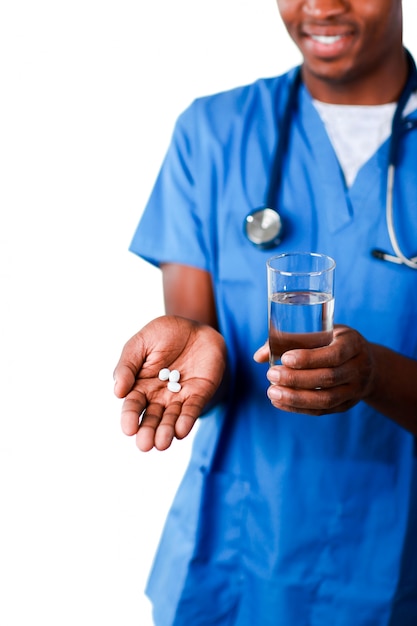 Joven médico mostrando pastillas y vaso de agua