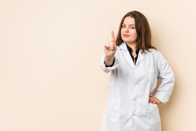 Joven médico mujer mostrando número uno con el dedo.