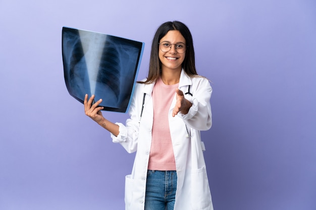 Joven médico mujer sosteniendo una radiografía dándose la mano para cerrar un buen trato