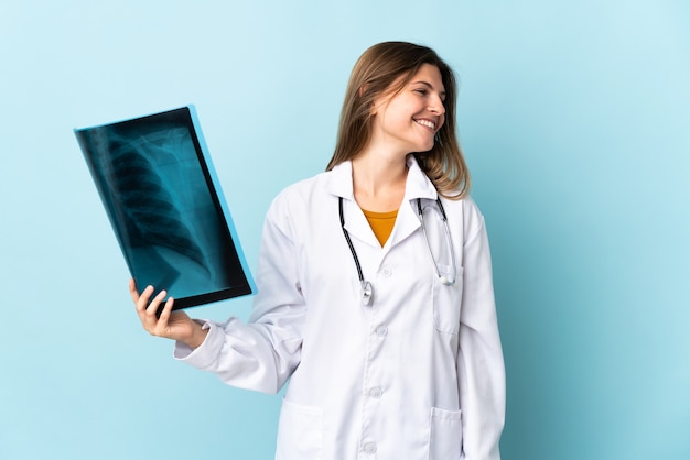 Joven médico mujer sosteniendo radiografía mirando de lado