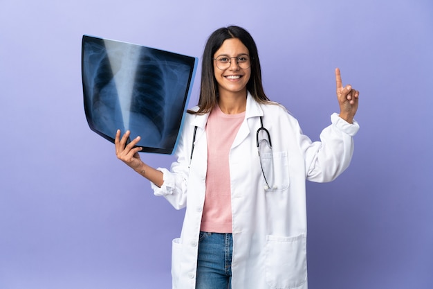 Joven médico mujer sosteniendo una radiografía mostrando y levantando un dedo en señal de lo mejor