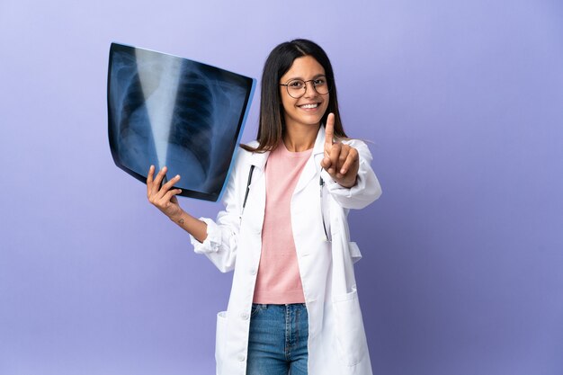 Joven médico mujer sosteniendo una radiografía mostrando y levantando un dedo