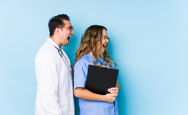 Joven médico pareja posando y gritando hacia