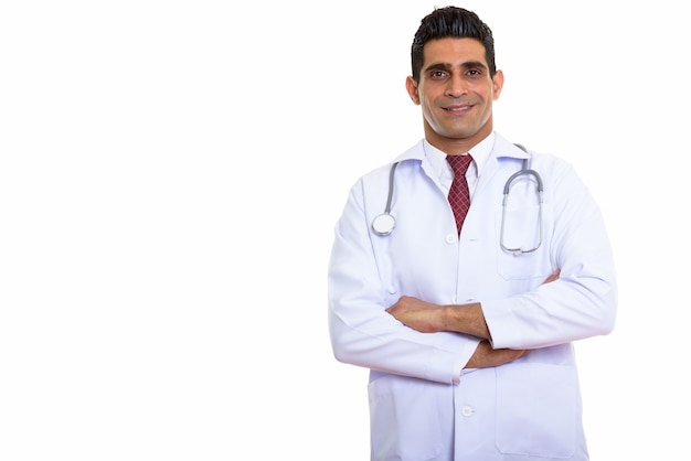 Joven médico persa feliz sonriendo con los brazos cruzados.