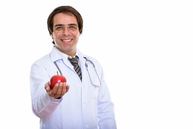 Joven médico persa feliz sonriendo mientras da una manzana roja