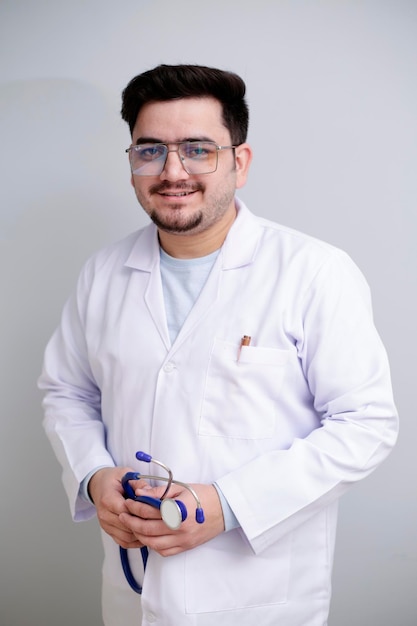 Foto un joven médico está de pie y sosteniendo un estetoscopio en la mano y sonriendo