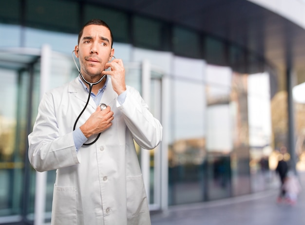 Joven médico reflexivo con un estetoscopio