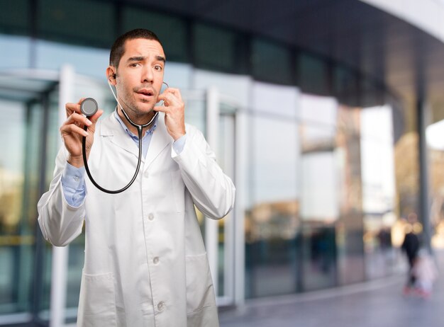 Joven médico reflexivo con un estetoscopio