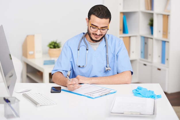 Joven médico sentado en el escritorio