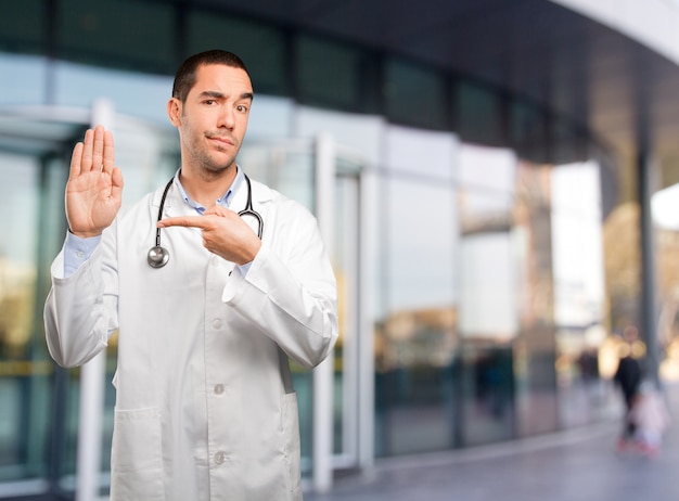 Joven médico serio mostrando su palma