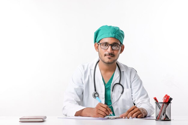 Joven médico de sexo masculino indio escribiendo en el bloc de notas en la clínica.