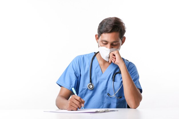 Joven médico de sexo masculino indio escribiendo en el bloc de notas en la clínica.