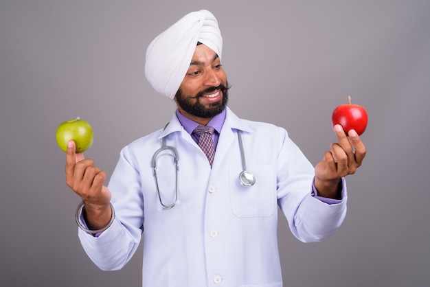 Joven médico sij indio sonriendo y sosteniendo apple
