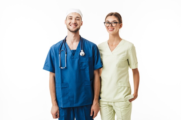 Foto joven médico sonriente con fonendoscopio en el cuello y bonita enfermera en anteojos y uniforme felizmente