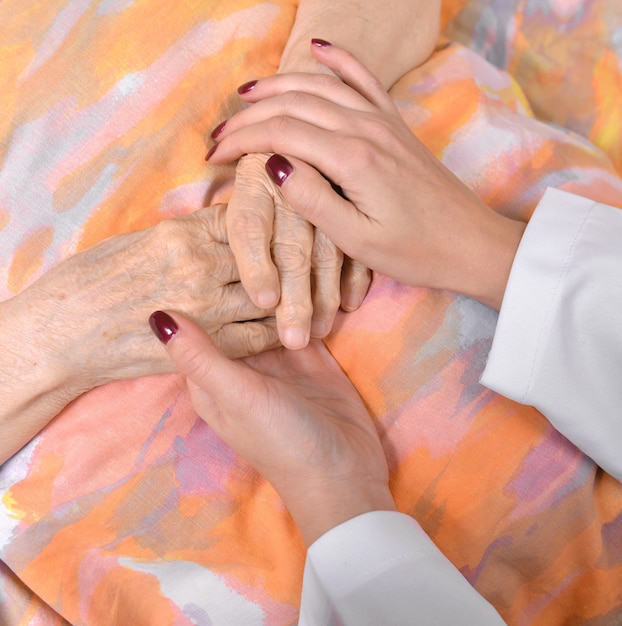 Foto joven médico sostiene la mano de la anciana