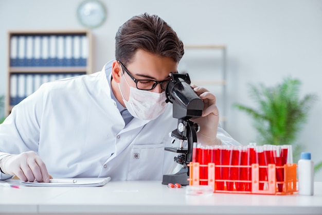 Joven médico trabajando en el laboratorio con microscopio