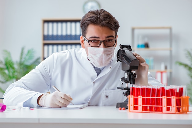 Joven médico trabajando en el laboratorio con microscopio