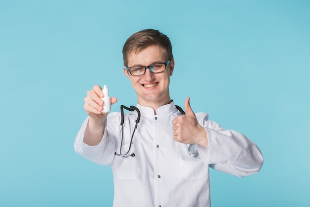 Joven médico en vasos recomendando gotas médicas