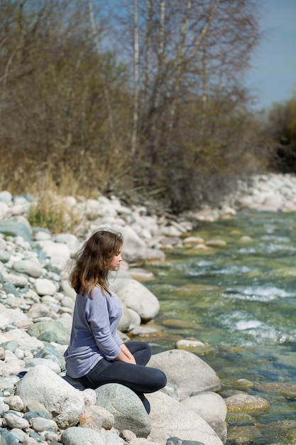 joven medita cerca del río