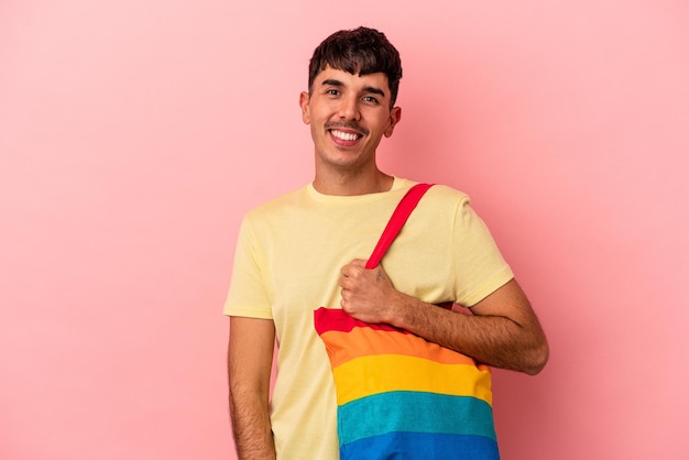 Foto joven mestizo hombre vestido con bolsa lgtb aislado sobre fondo de color rosa