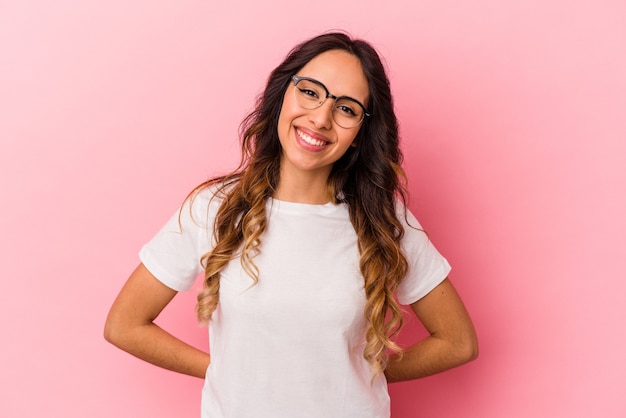 Joven mexicana aislada sobre fondo rosa feliz, sonriente y alegre.