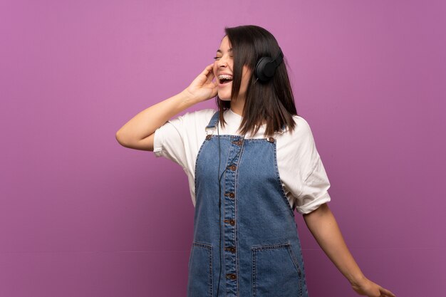 Foto joven mexicana sobre aislado escuchando música con auriculares