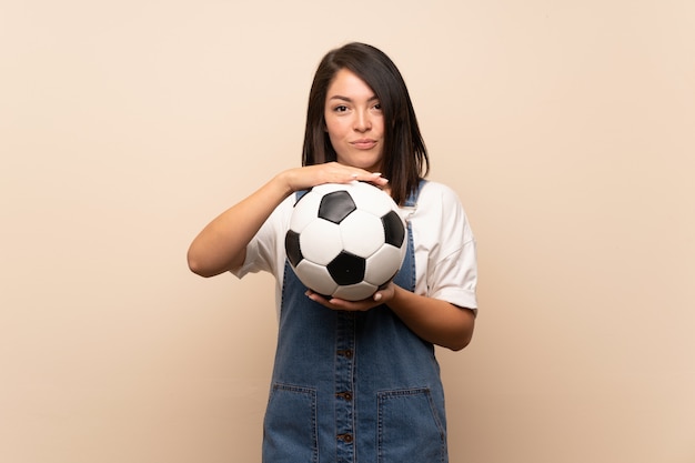 Joven mexicana sobre aislado sosteniendo un balón de fútbol