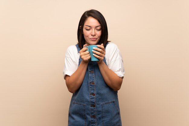 Joven mexicana sobre aislado sosteniendo una taza de café caliente