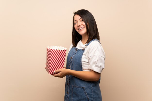 Joven mexicana sobre aislado sosteniendo un tazón de palomitas de maíz