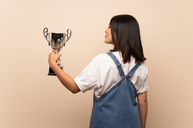 Joven mexicana sobre aislado sosteniendo un trofeo